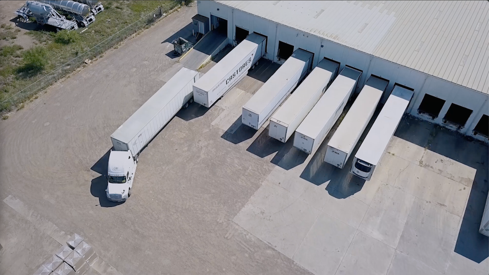 Aerial view of CrossDockNow warehouse dock operations with several trucks at loading bays